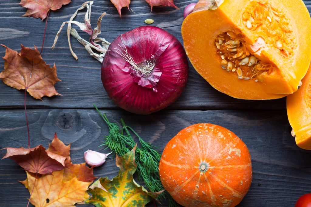 Ripe pumpkins and autumn leaves on wooden background